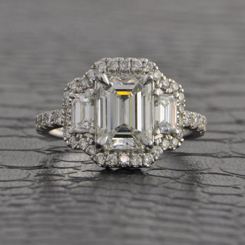 Premium Jewelry Now Available At Special Discounts Magnificent Three Stone Emerald Cut Halo Engagement Ring in White Gold